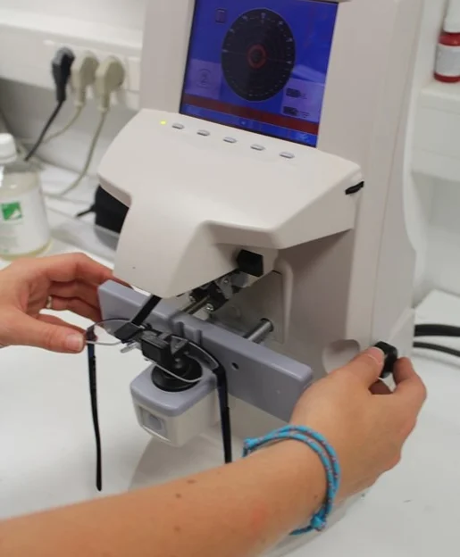 Mains ajustant des lunettes sur une machine d'opticien avec écran d'affichage à Loire Authion et à Mazé-Millon près d'Angers dans le Maine-et-Loire 49