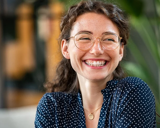 Femme souriante avec des lunettes rondes et des taches de rousseur, portant un haut à pois à Loire-Authion et à Mazé-Millon près d'Angers dans le Maine-et-Loire 49