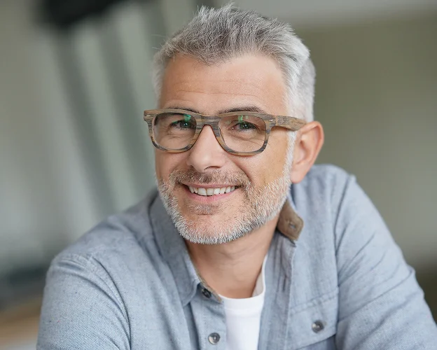 Homme souriant d'âge moyen, cheveux gris, lunettes en bois, chemise décontractée à Loire-Authion et à Mazé-Millon près d'Angers dans le Maine-et-Loire 49