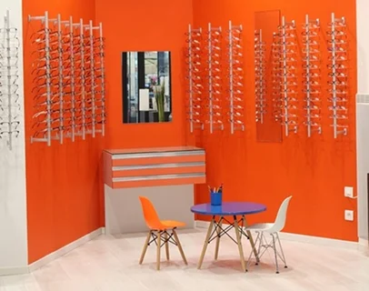 Magasin d'optique aux murs orange vif, avec lunettes exposées, table et chaises colorées à Loire-Authion et à Mazé-Millon près d'Angers dans le Maine-et-Loire 49